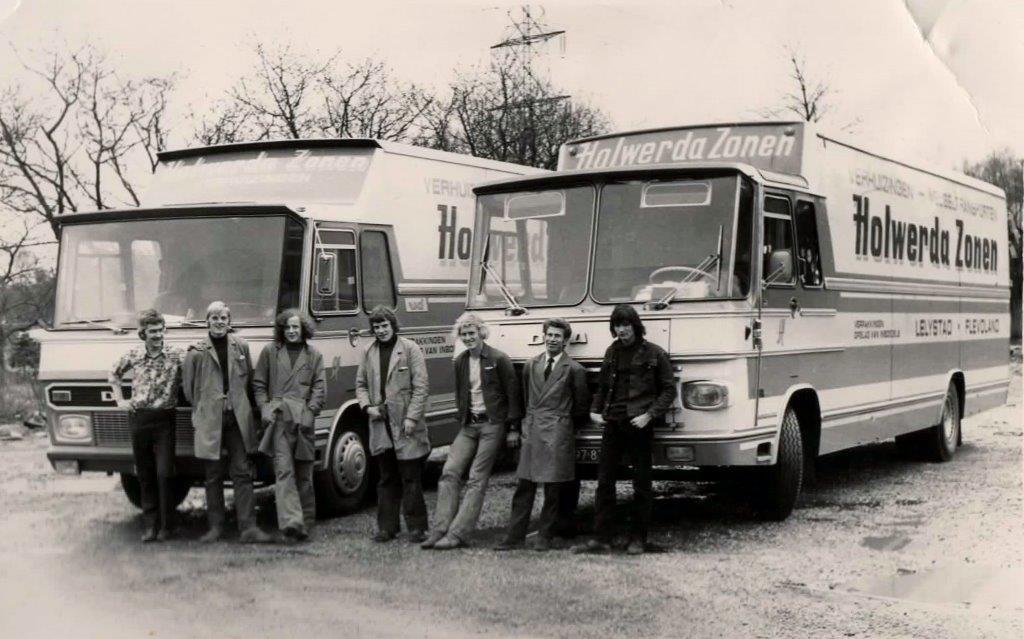 Oude zwart-witfoto van verhuizers voor twee verhuiswagens van Holwerda Zonen